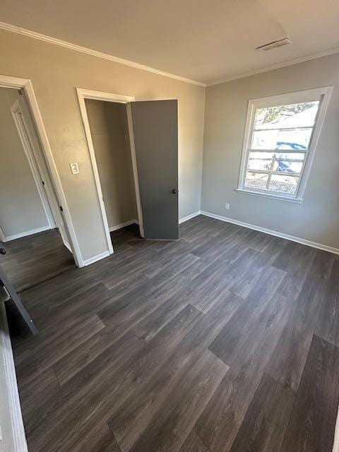 unfurnished bedroom with a closet, crown molding, and dark hardwood / wood-style floors