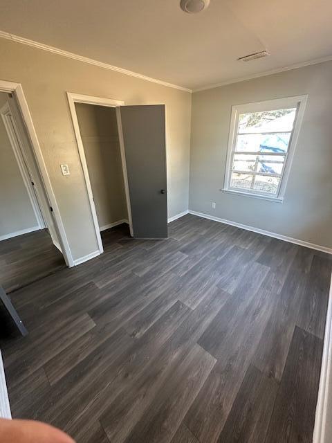 unfurnished bedroom featuring ornamental molding, a closet, and dark hardwood / wood-style floors