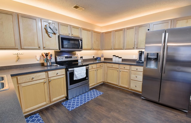 kitchen featuring a textured ceiling, stainless steel appliances, dark wood-type flooring, visible vents, and light brown cabinetry