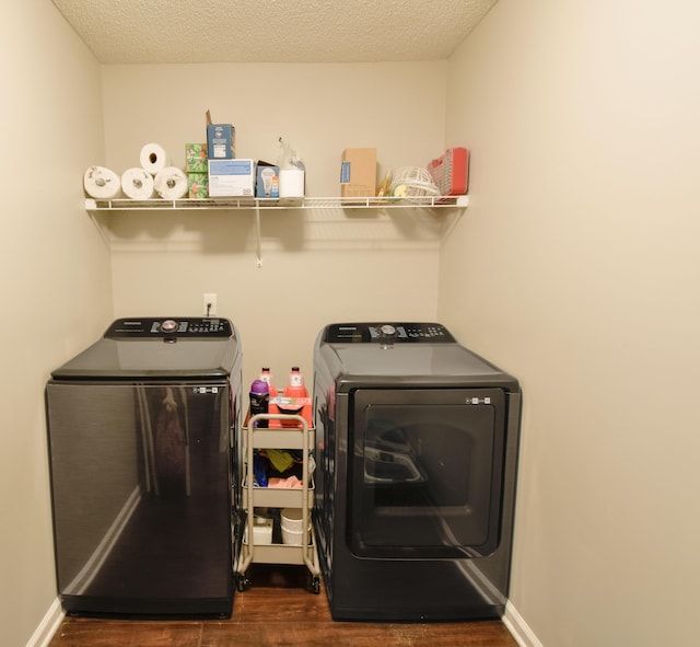 clothes washing area with laundry area, dark wood finished floors, washer and clothes dryer, and baseboards