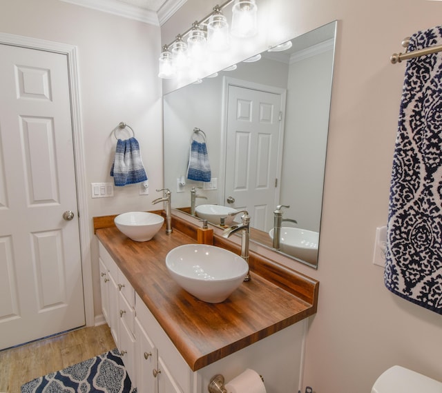 full bathroom with crown molding, a sink, and wood finished floors