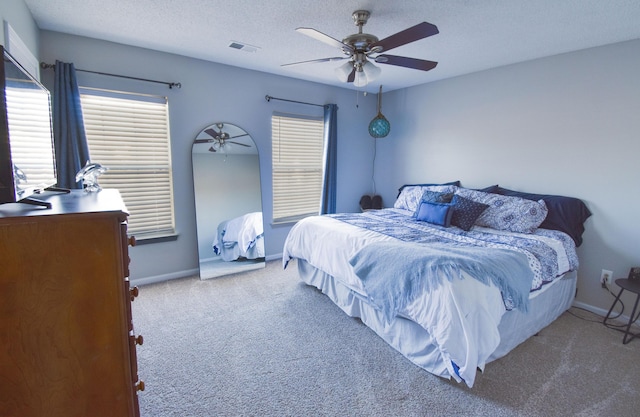 carpeted bedroom featuring a ceiling fan, visible vents, a textured ceiling, and baseboards