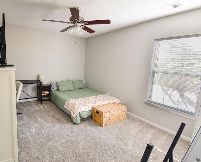 carpeted bedroom featuring a textured ceiling, ceiling fan, visible vents, and baseboards