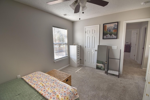 carpeted bedroom with a ceiling fan, baseboards, visible vents, and a textured ceiling