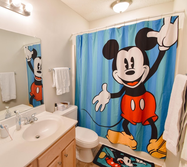 full bathroom with a shower with shower curtain, a textured ceiling, toilet, and vanity