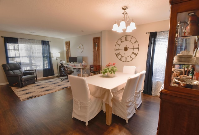 dining space featuring dark wood-style floors, a textured ceiling, a chandelier, and baseboards