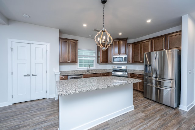 kitchen featuring pendant lighting, sink, appliances with stainless steel finishes, a center island, and dark hardwood / wood-style flooring