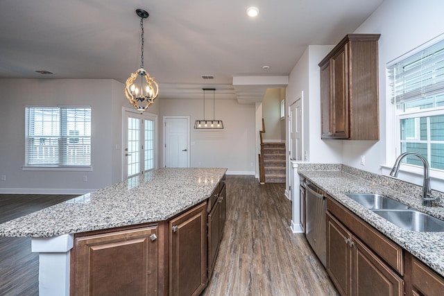 kitchen with dark wood-type flooring, sink, a center island, stainless steel dishwasher, and light stone countertops