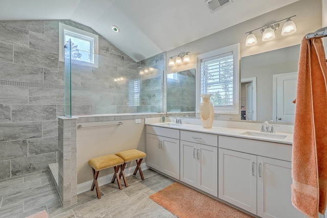 bathroom featuring vanity, tiled shower, and vaulted ceiling