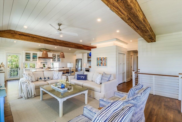 living room featuring beam ceiling, ceiling fan, dark hardwood / wood-style floors, and wooden walls