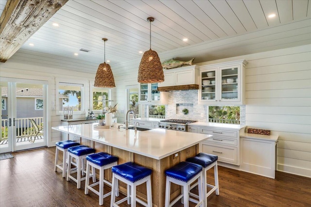 kitchen featuring pendant lighting, a center island with sink, stove, sink, and white cabinets