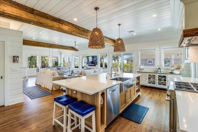 kitchen with appliances with stainless steel finishes, sink, hanging light fixtures, a kitchen island with sink, and beam ceiling