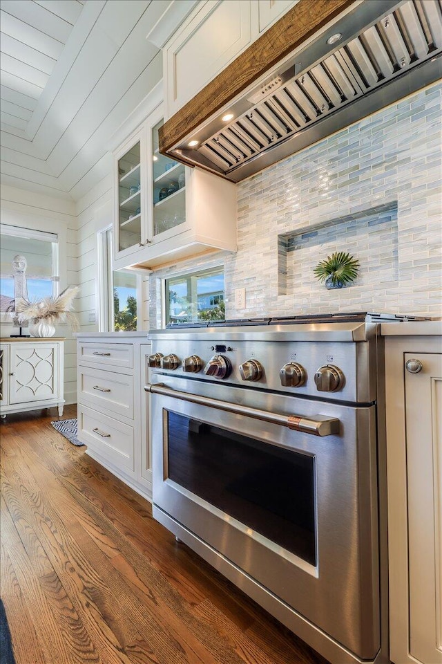 kitchen featuring backsplash, dark hardwood / wood-style floors, premium range hood, high end stainless steel range oven, and white cabinets