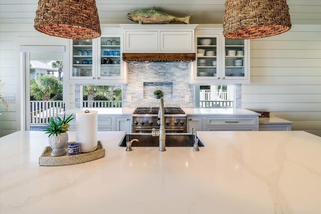 kitchen featuring high end range, a healthy amount of sunlight, and wooden walls