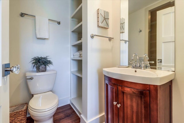 bathroom with built in shelves, hardwood / wood-style floors, toilet, and vanity