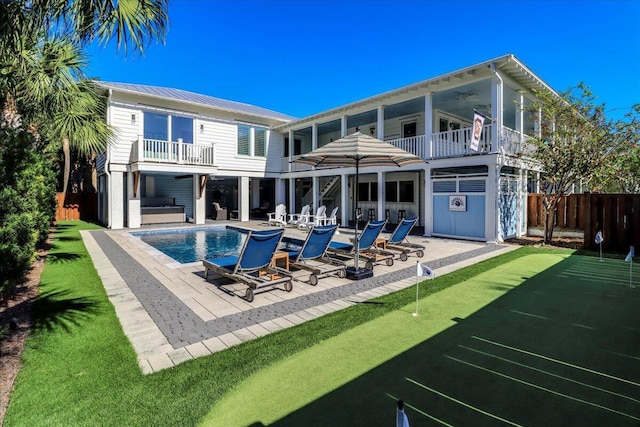 rear view of property featuring a pool with hot tub, ceiling fan, a balcony, and a patio