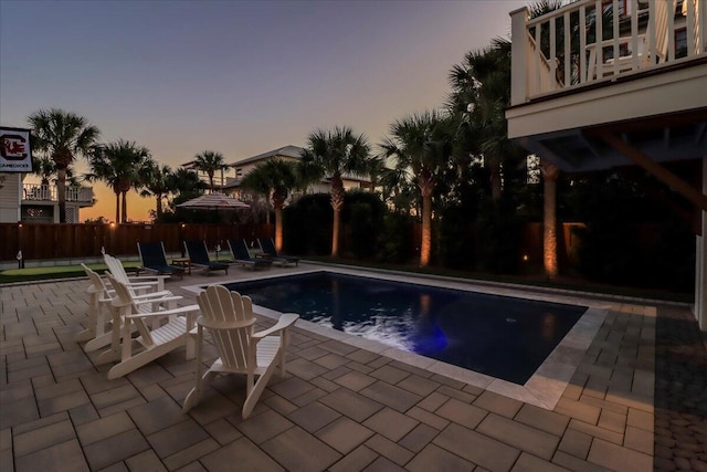 pool at dusk featuring a patio