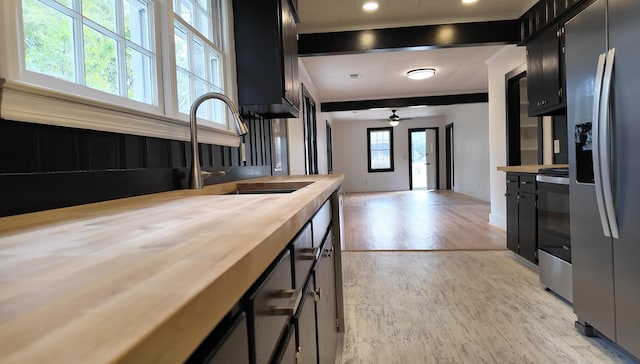 kitchen featuring wooden counters, sink, ceiling fan, light wood-type flooring, and stainless steel appliances