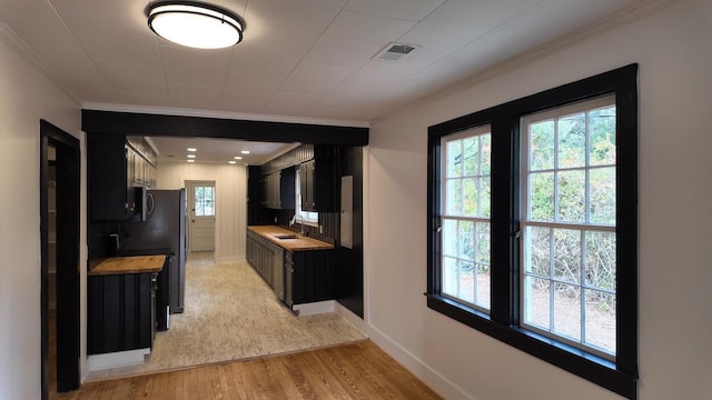 kitchen with light hardwood / wood-style floors, crown molding, and sink