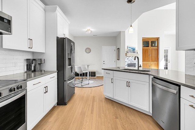 kitchen featuring backsplash, sink, hanging light fixtures, appliances with stainless steel finishes, and white cabinets