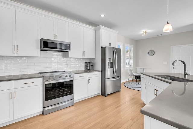 kitchen featuring white cabinetry, sink, hanging light fixtures, and stainless steel appliances