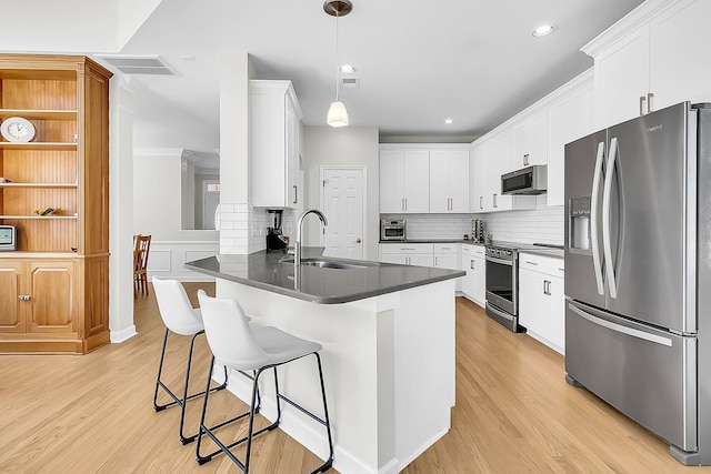 kitchen with white cabinetry, kitchen peninsula, stainless steel appliances, hanging light fixtures, and sink