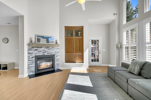 living room with ceiling fan, wood-type flooring, and a high ceiling