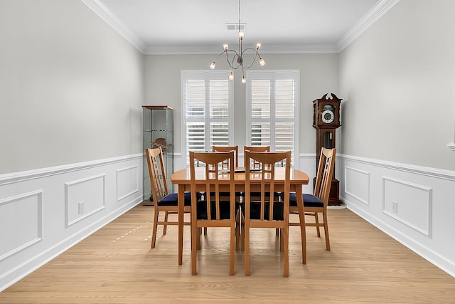 dining room featuring light hardwood / wood-style flooring, ornamental molding, and a notable chandelier