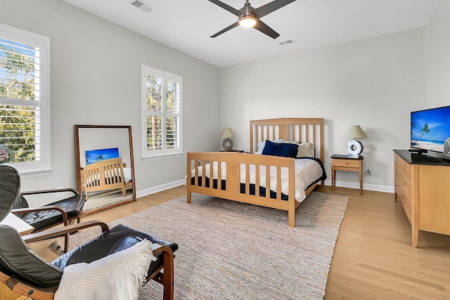 bedroom featuring ceiling fan, multiple windows, and light hardwood / wood-style flooring