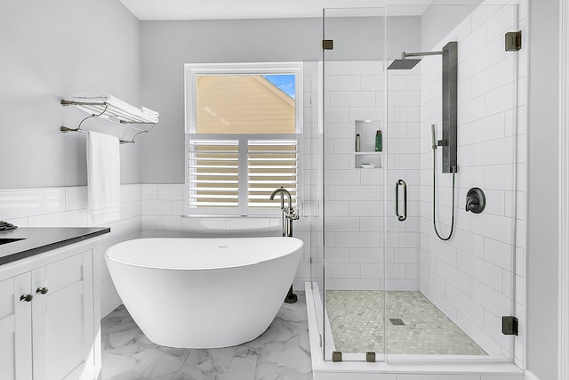 bathroom with tile walls, vanity, and separate shower and tub