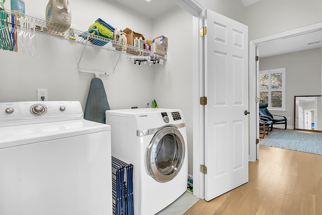 washroom featuring washing machine and dryer and light hardwood / wood-style flooring