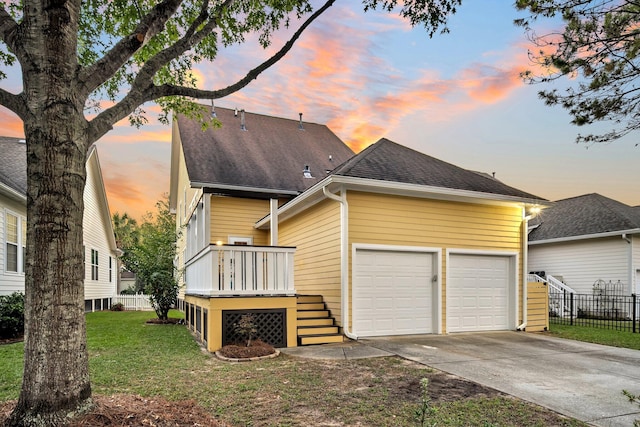 back house at dusk with a garage and a yard