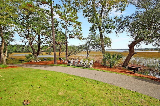 surrounding community with a water view and a lawn