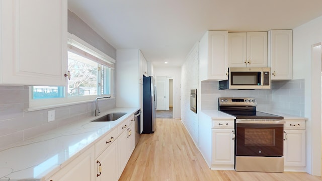 kitchen with sink, stainless steel appliances, light hardwood / wood-style floors, and white cabinets