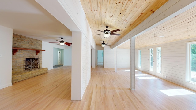 unfurnished living room featuring wood-type flooring, a stone fireplace, wooden ceiling, and french doors