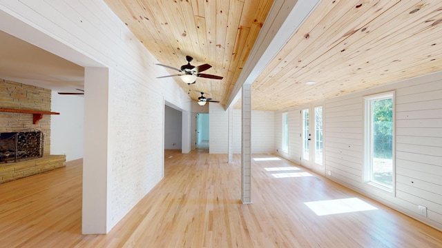 interior space with a fireplace, wooden ceiling, wood walls, and light wood-type flooring