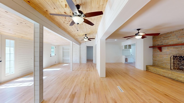 unfurnished living room with a stone fireplace, light hardwood / wood-style floors, and wooden ceiling