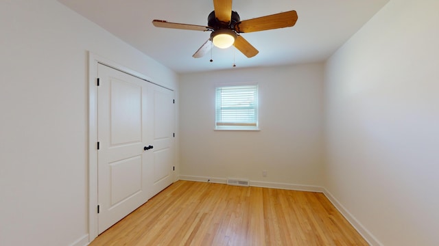 unfurnished bedroom with ceiling fan, a closet, and light wood-type flooring