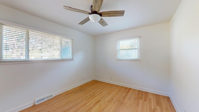 empty room with plenty of natural light, ceiling fan, and light wood-type flooring