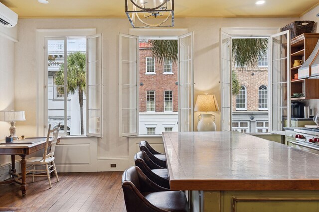 dining area featuring hardwood / wood-style floors, a notable chandelier, and a wall unit AC