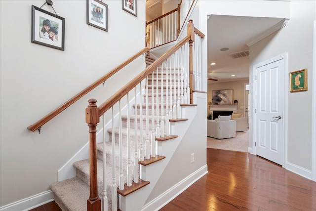 stairway with hardwood / wood-style flooring and ornamental molding