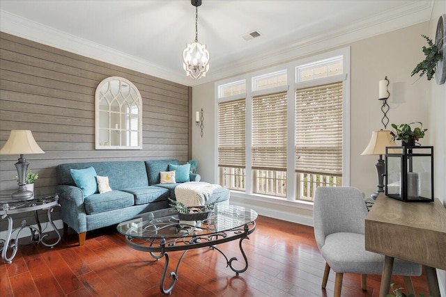 living room with a notable chandelier, wooden walls, dark hardwood / wood-style floors, and crown molding