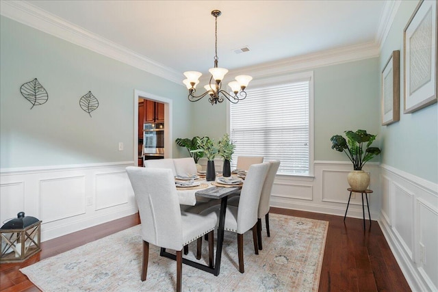 dining room with dark hardwood / wood-style flooring, ornamental molding, and a chandelier