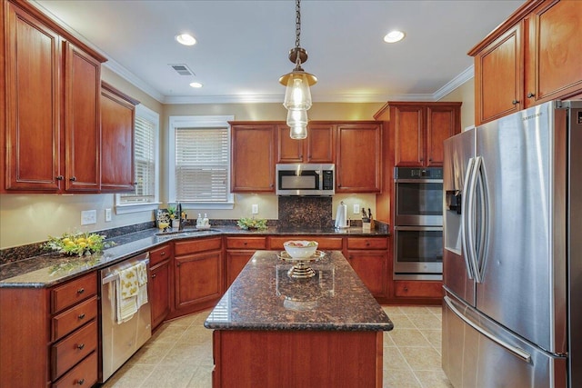 kitchen with a kitchen island, decorative light fixtures, stainless steel appliances, dark stone countertops, and sink