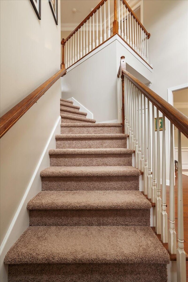 staircase with crown molding and a towering ceiling