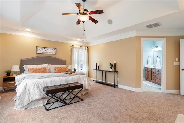 bedroom with a tray ceiling, light carpet, ornamental molding, ceiling fan, and ensuite bathroom