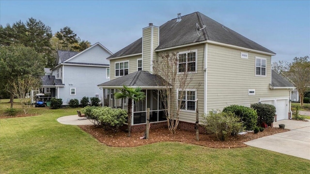 back of property with a garage, a sunroom, and a lawn