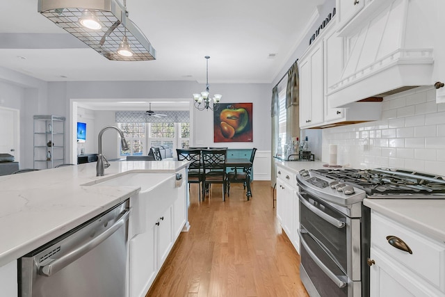 kitchen featuring pendant lighting, white cabinets, custom exhaust hood, stainless steel appliances, and light wood-type flooring