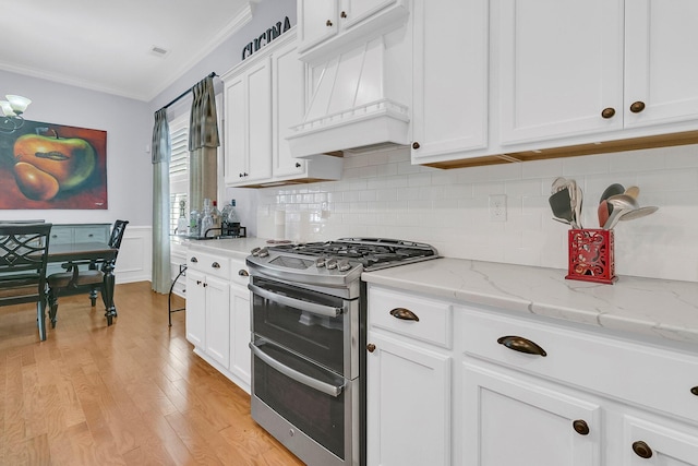 kitchen with white cabinets, double oven range, ornamental molding, light stone counters, and custom range hood