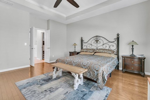 bedroom featuring ceiling fan, ornamental molding, a raised ceiling, and hardwood / wood-style floors